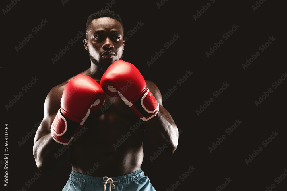 African guy posing in boxing stance over black background