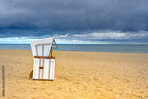 Lonely beach with a beach chair on Usedom overlooking the sea to dramatic looking storm clouds.