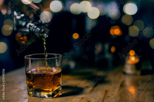 Photo glass of whiskey and ice on wooden table