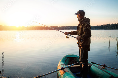 Male fisherman at dawn on the lake catches a fishing rod. Fishing hobby vacation concept. Copy space.