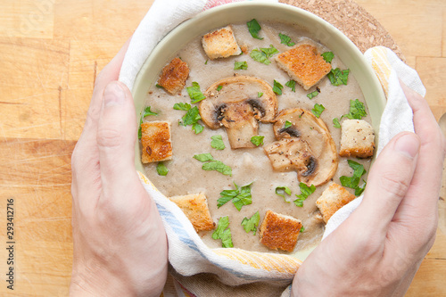 Cream of champignons soup with parsley and croutons, on a wooden background, hot dish