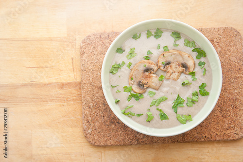 Cream of champignons soup with parsley and croutons, on a wooden background. Hot dish. Top view, food.