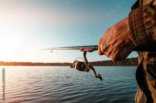 Photography Hands of a man in a Urp plan hold a fishing rod, a fisherman catches fish at dawn