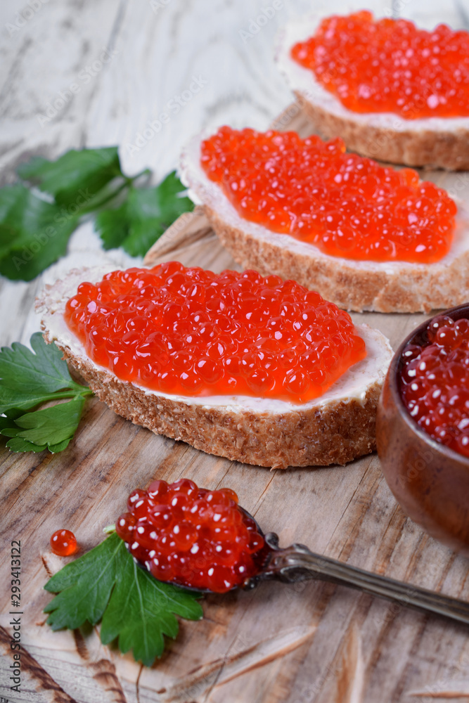 Sandwiches with bran bread, red caviar and butter on white wooden table