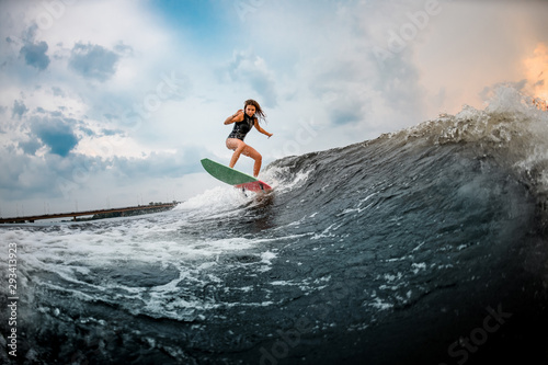 Young girl surfing on a wakeboard in the river near forest photo