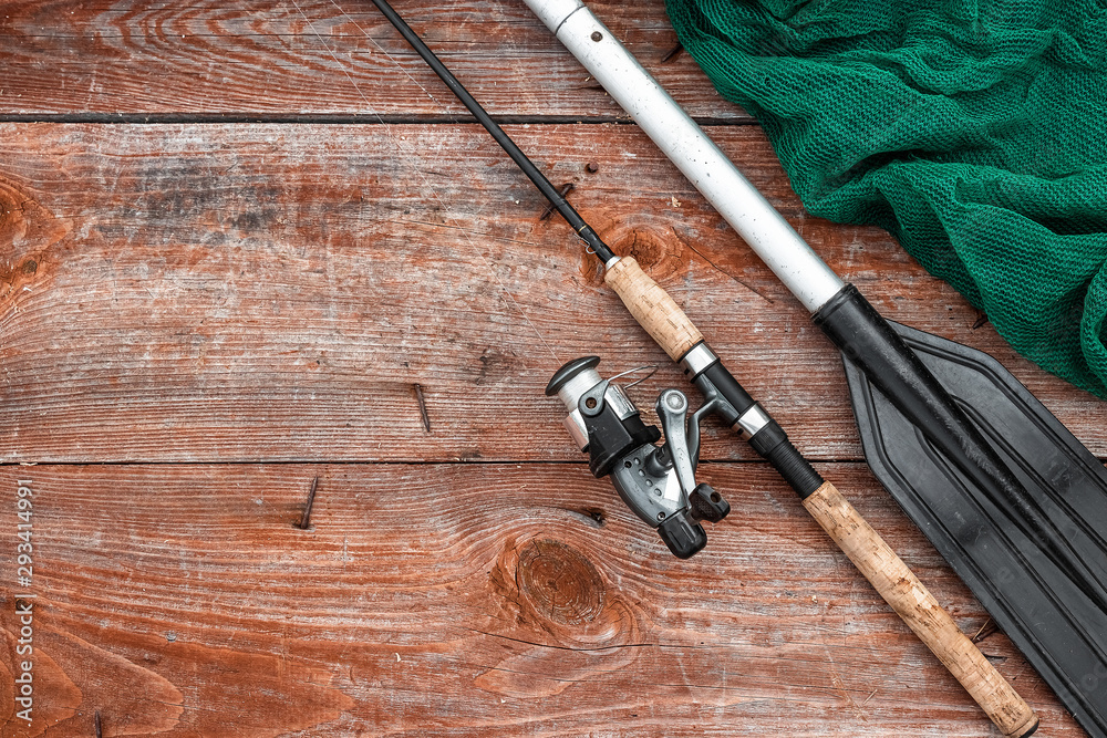 Paddle fishing rod and fishing net on a wooden background top view