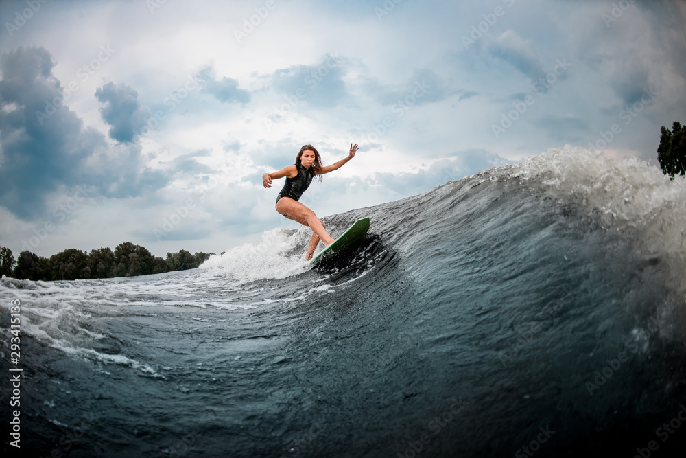 Young girl wakesurfing on a board in the river near forest
