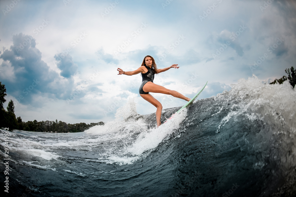 Female wakesurfer makes stunts on a board