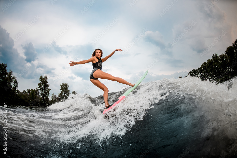 Female wakesurfer does stunts on a board