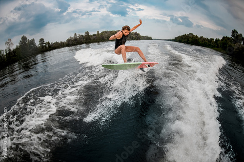 Girl wakesurfer jumps with the surf board photo