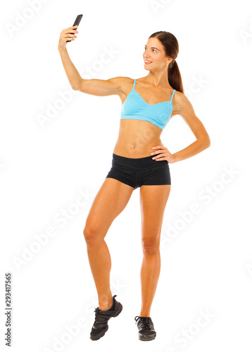 Young fitness brunette woman in blue top and black shorts posing isolated on white background