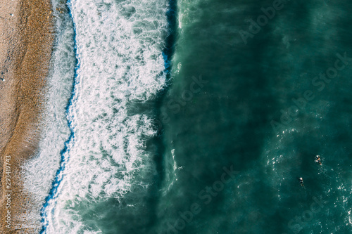 The surfer sails on a surfboard in a calm ocean, top view