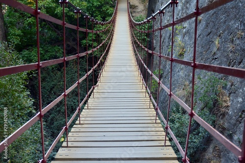 Fototapeta Naklejka Na Ścianę i Meble -  Camino pasando por un puente colgante de hierro y madera