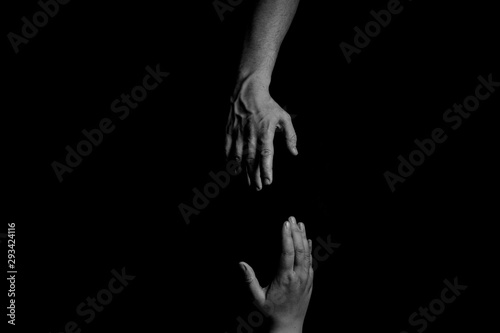 Helping Hand, Hand reaching, trying to pull up and rescue, black background, copy space