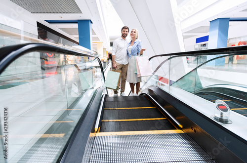 Couple Walking Up Escalator Shopping In Hypermarket
