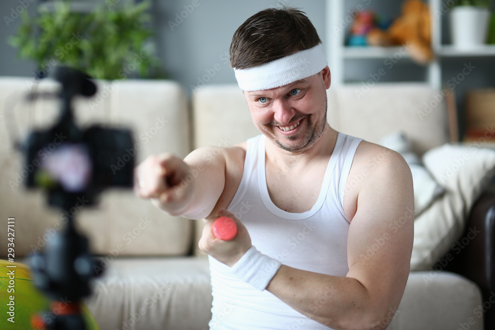 Happy Blogger with Dumbbell Training in Apartment. Smiling Sportsman Recording Video on Digital Camcorder for Sport Blog. Cheerful Man Doing Fitness Exercise at Home. Bearded Male Practice Aerobic Happy Blogger with Dumbbell Training in Apartment. Smiling Sportsman Recording Video on Digital Camcorder for Sport Blog. Cheerful Man Doing Fitness Exercise at Home. Bearded Male Practice Aerobic