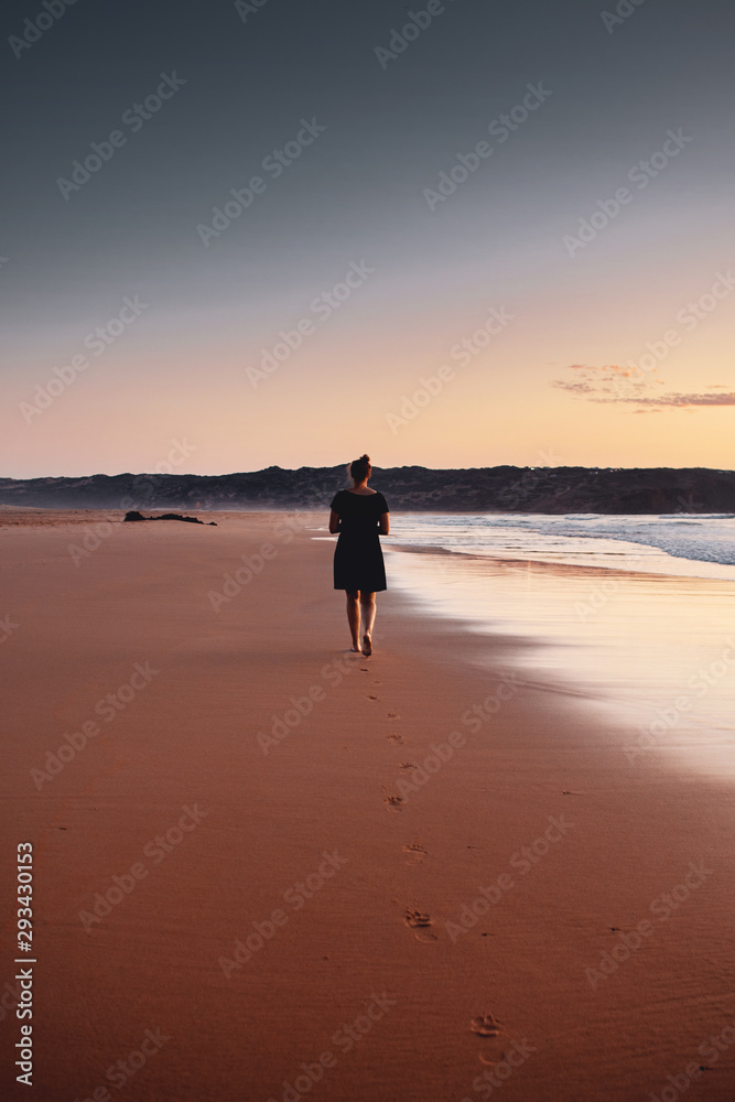 Silhouette of a girl in colorful sunset gradient at a peaceful beach on a tropical beach. Praia da Bordeira at the Algarve Coast in Portugal, Atlantic Ocean Silhouette of a girl in colorful sunset gradient at a peaceful beach on a tropical beach. Praia da Bordeira at the Algarve Coast in Portugal, Atlantic Ocean