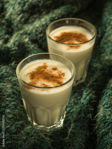 Eggnog. Traditional Christmas drink made from raw chicken eggs and milk with cinnamon in glass.