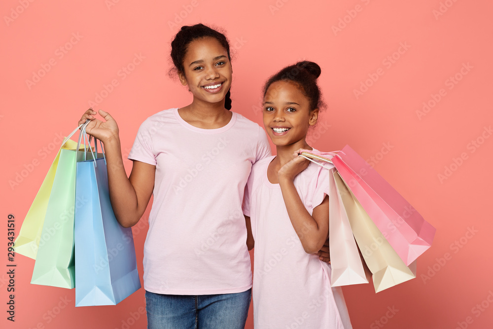 African sisters with shopping bags looking at camera and smiling African sisters with shopping bags looking at camera and smiling