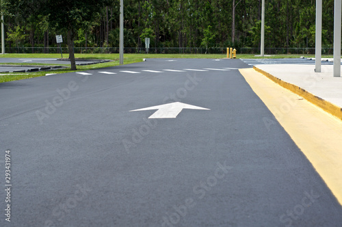 Looking down the length of an empty parking lot with arrow pointing in direction to go, with crosswalk and sidewalk. © Stephen Orsillo