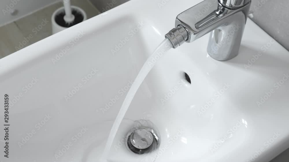 White ceramic bidet at modern restroom interior. Water is running. Nobody White ceramic bidet at modern restroom interior. Water is running. Nobody