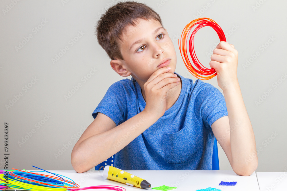 Kid holding 3d pen and colorful filaments for 3 d pen and thinking