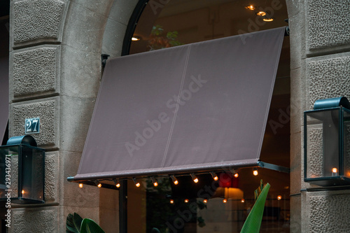Blank brown black awning over cafe windows mockup. Empty awning mounted on the ancient wall in european town. photo