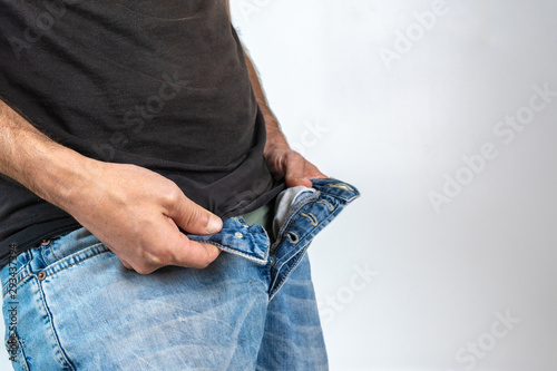 man with blue jeans and black shirt opening the zipper of his pants, isolated on White background