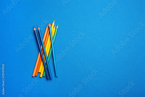 Color pencils on blue background  flat lay. Space for text