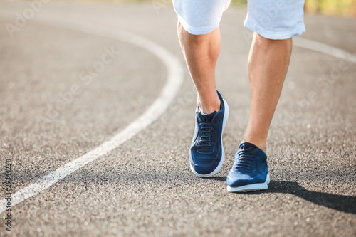 Sporty young man running at the stadium, closeup