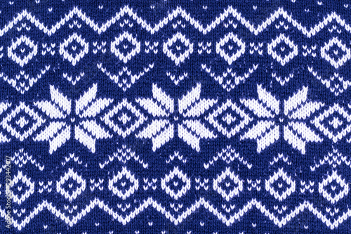 Warm Christmas blue sweater with snowflakes. Vintage Scandinavian Woolen Jumper Pattern. Closeup. Background. Knitting pattern with snowflakes.