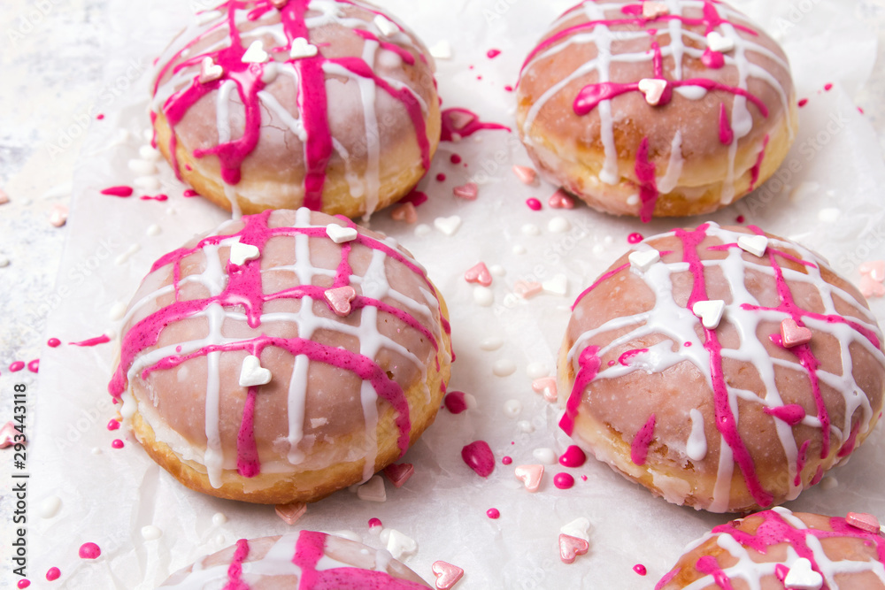 Traditional Polish donuts with pink frosting and heart sprinkles on light background. Tasty doughnuts with jam. Traditional Polish donuts with pink frosting and heart sprinkles on light background. Tasty doughnuts with jam.