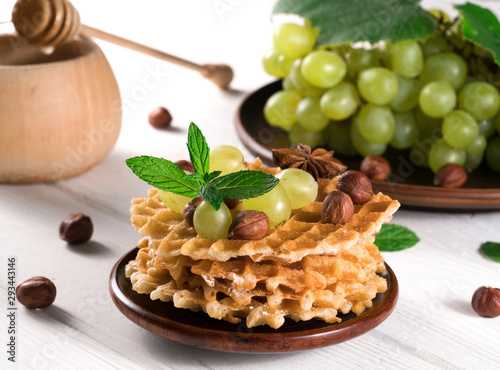 waffles with honey and grapes on a wooden background