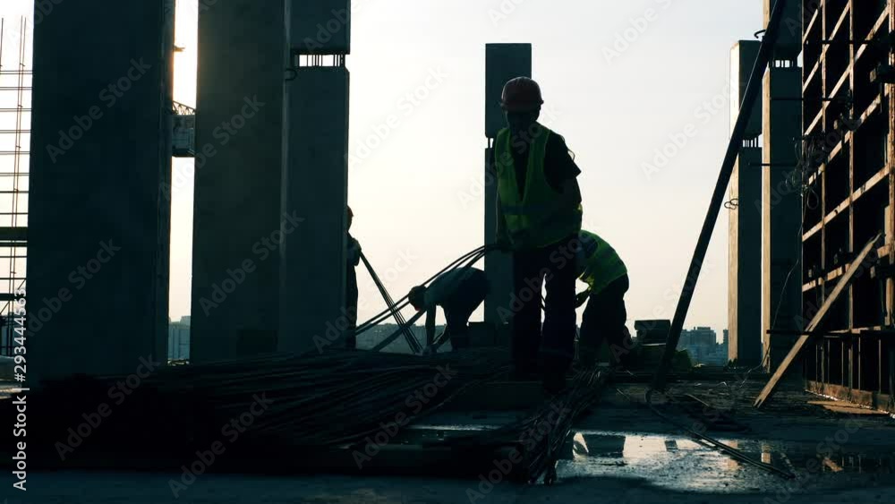 Men moving metal poles while building a house. Men moving metal poles while building a house.
