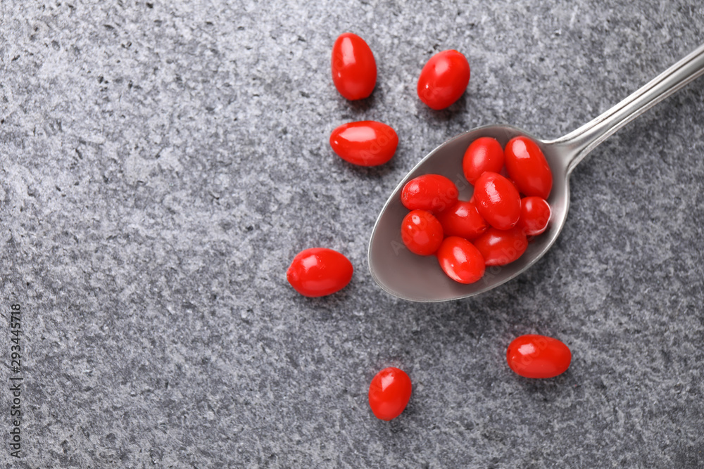 Spoon with fresh goji berries on grey background, flat lay. Space for text Spoon with fresh goji berries on grey background, flat lay. Space for text