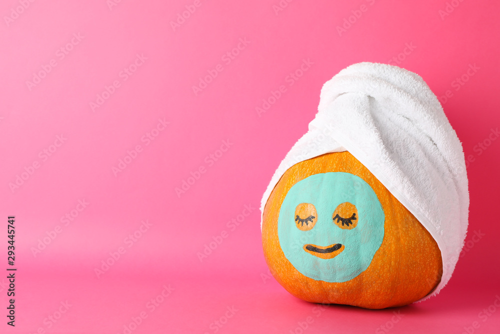 Pumpkin with facial mask and towel on pink background, copy space - obrazy, fototapety, plakaty 