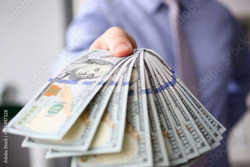 Man in suit and tie hold in arm pack of hundred dollar bills closeup. Stock market financial illegal freedom exchange earn pile rich present gift employer prepayment service gratitude concept