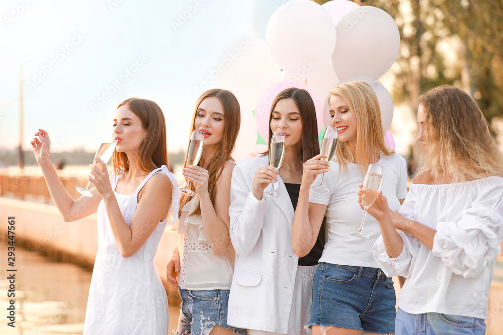 Beautiful young women drinking champagne at hen party outdoors Beautiful young women drinking champagne at hen party outdoors