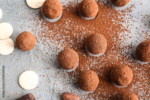 Tasty sweet truffles with cacao powder on light background