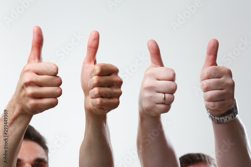 A group of people male hands on a gray background holds a thumb up expressing agreement finger OK concept is large closeup concept