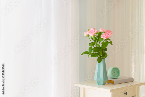 Beautiful rose flowers in vase on table near window