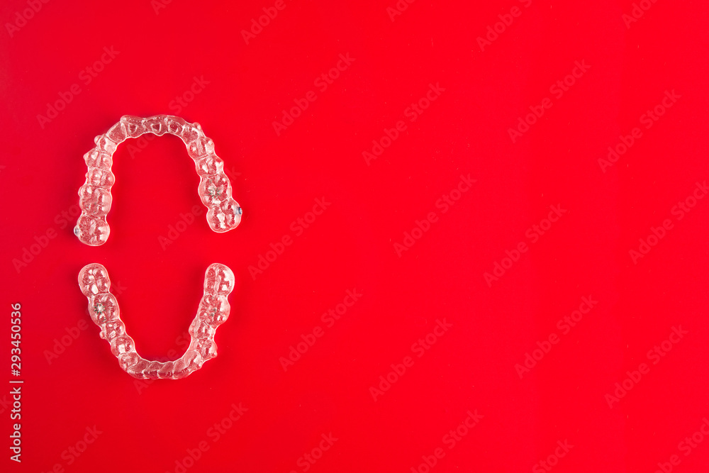 Top view of invisalign braces or invisible retainers on red background, new orthodontic equipment