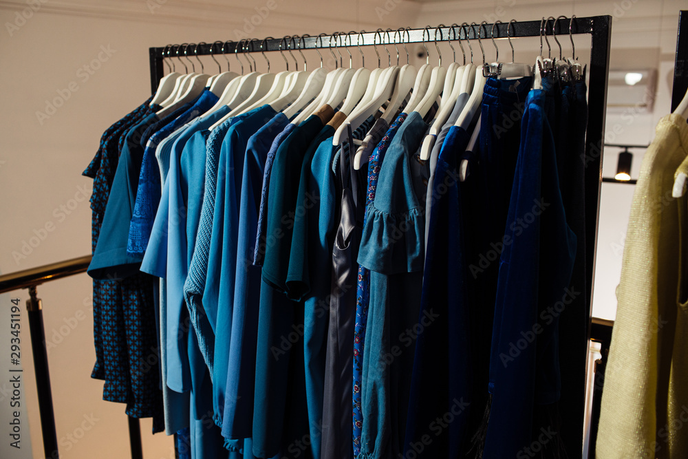 Fototapeta premium Close-up view of various stylish clothes hanging on hangers in boutique. Clothes