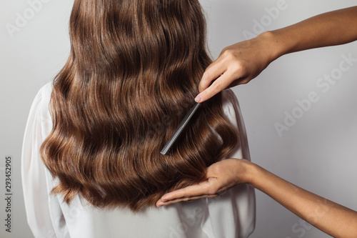 Closeup of female hands of hairdresser or coiffeur makes hairstyle. Hair