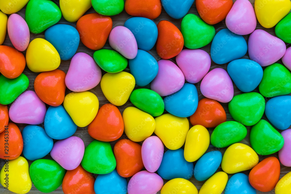 Background in the form of hearts made of milk chocolate, coated with multi-colored glaze, top view Background in the form of hearts made of milk chocolate, coated with multi-colored glaze, top view