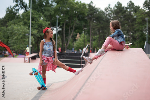 Two female skaters best friends hangout at the skate park on sunset .Laughing and fun. photo