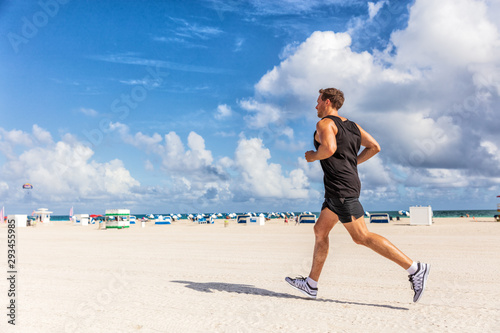 Fit man running jogging exercising on South Beach, Miami, Florida on beach. Runner athlete working out healthy active sporty lifestyle outdoors workout.