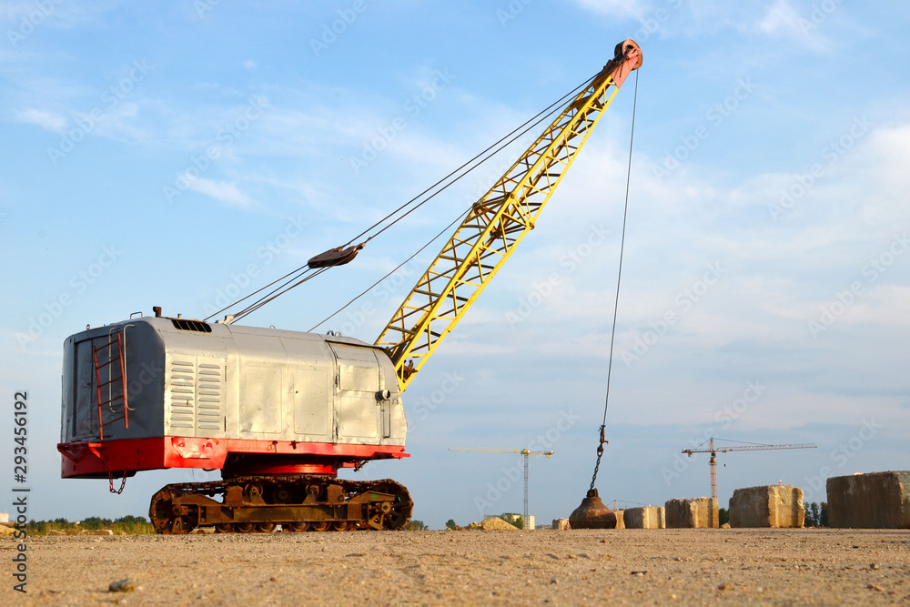 Large crawler crane or dragline excavator with a heavy metal wrecking ball on a steel cable. Wrecking balls at construction sites. Dismantling and demolition of buildings and structures - Image