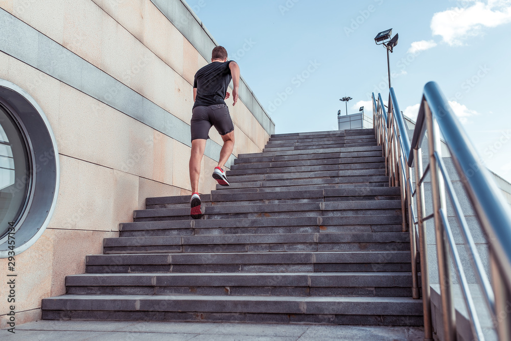 man runs up stairs, view from back, in summer, autumn spring in city, free space for motivation text, sportswear, active lifestyle, fitness, outdoor sports workout.