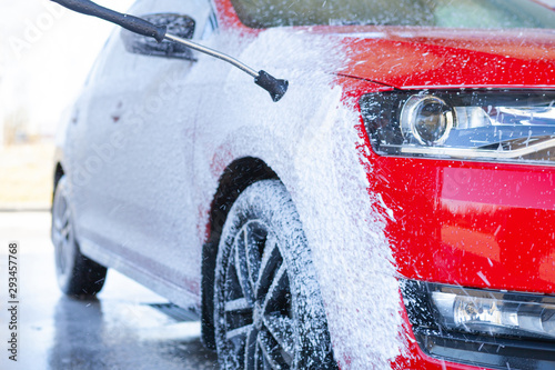 Car cleaning. Wash red car with soap. High pressure water washing
